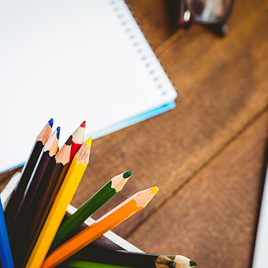 close up of colored pencils in holder with notebook