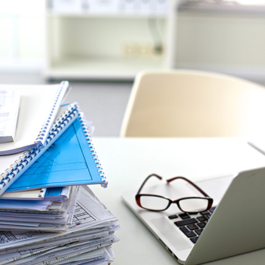 Stack of Notebooks & Laptop on Desk