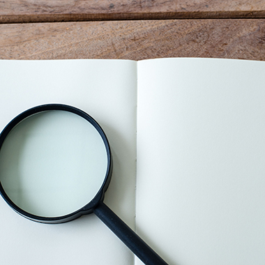 Magnifying Glass on White Open Notebook
