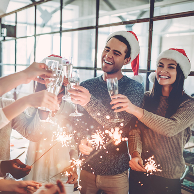 Coworkers clinking champagne glasses at office holiday party