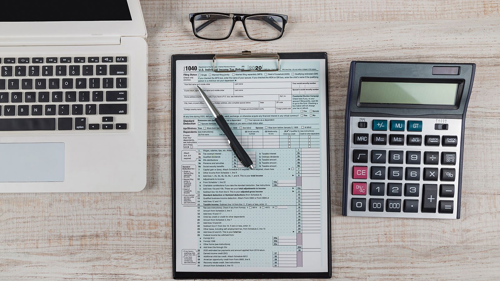 Tax forms 1040 with laptop, pen and calculator