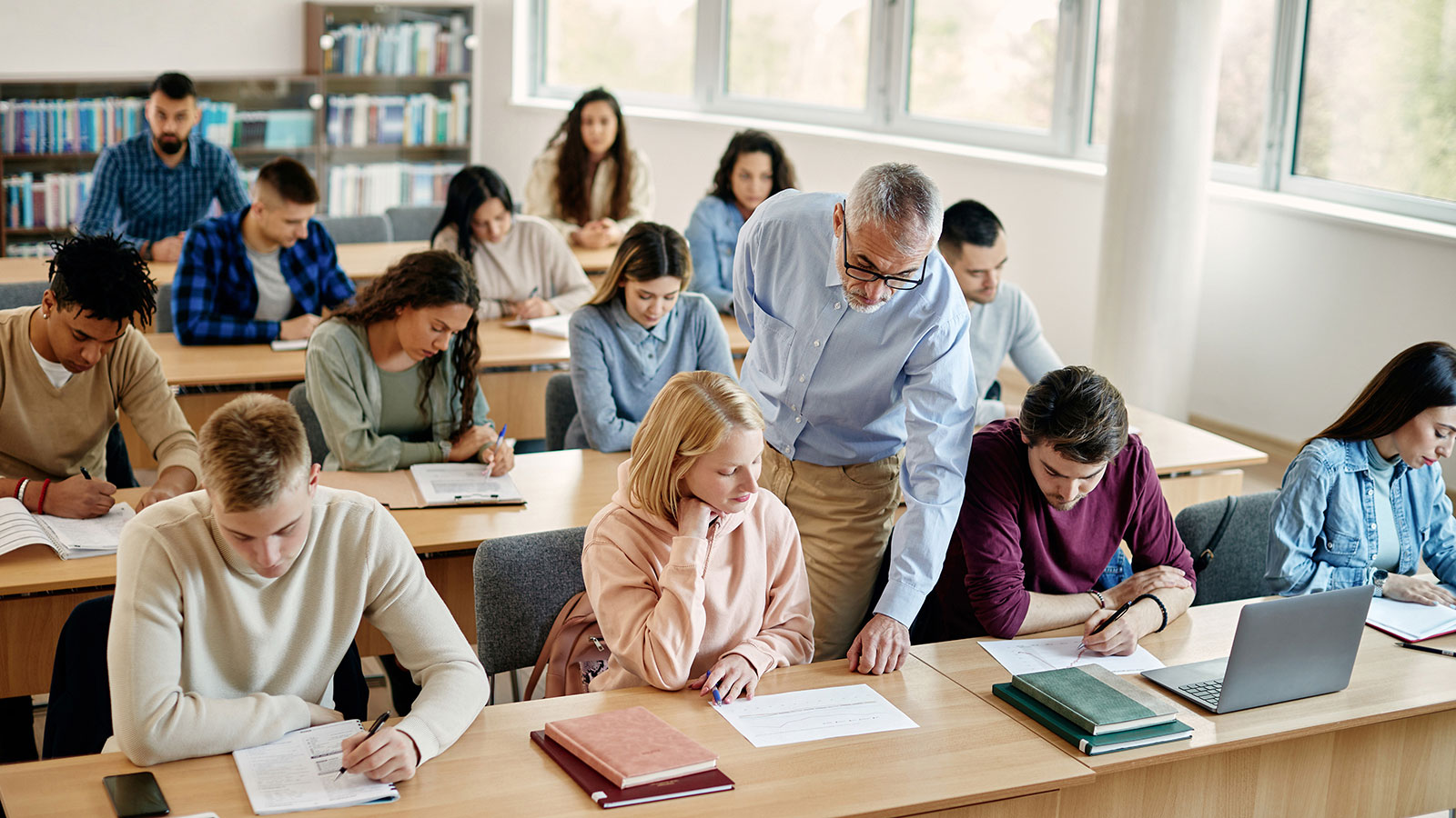 Senior teacher assists his students during a class at college classroom