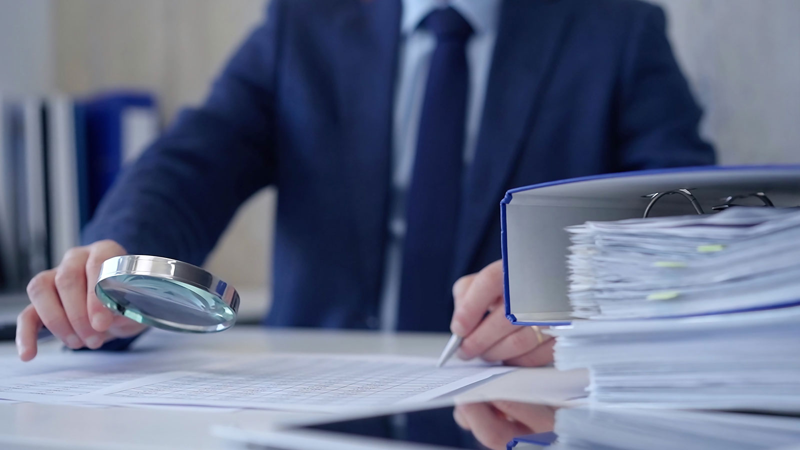 Adult businessman or auditor examining documents with magnifying glass