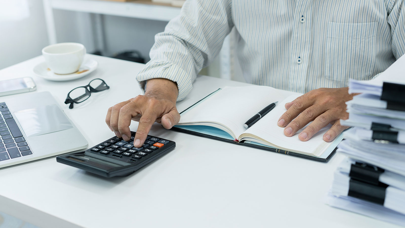 office employee works on desk, using calculator to manage financial documents and accounts