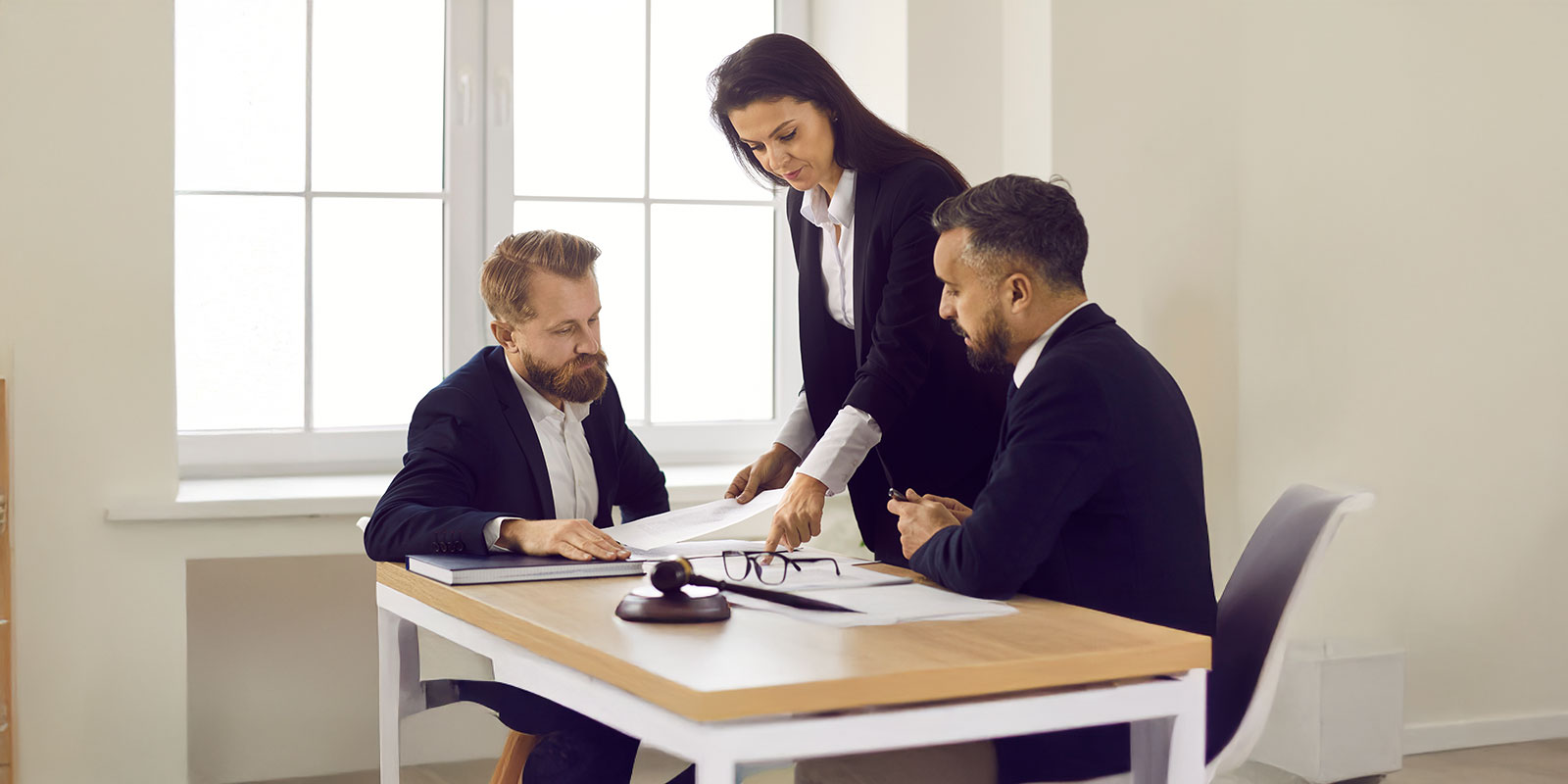 Diverse lawyers sit at desk at meeting talk discuss paperwork documents together