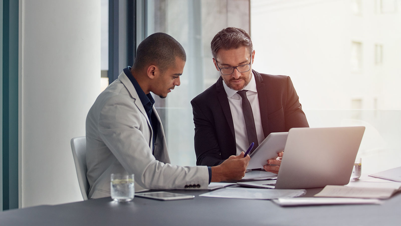 Tablet laptop and business men planning in a conference room meeting