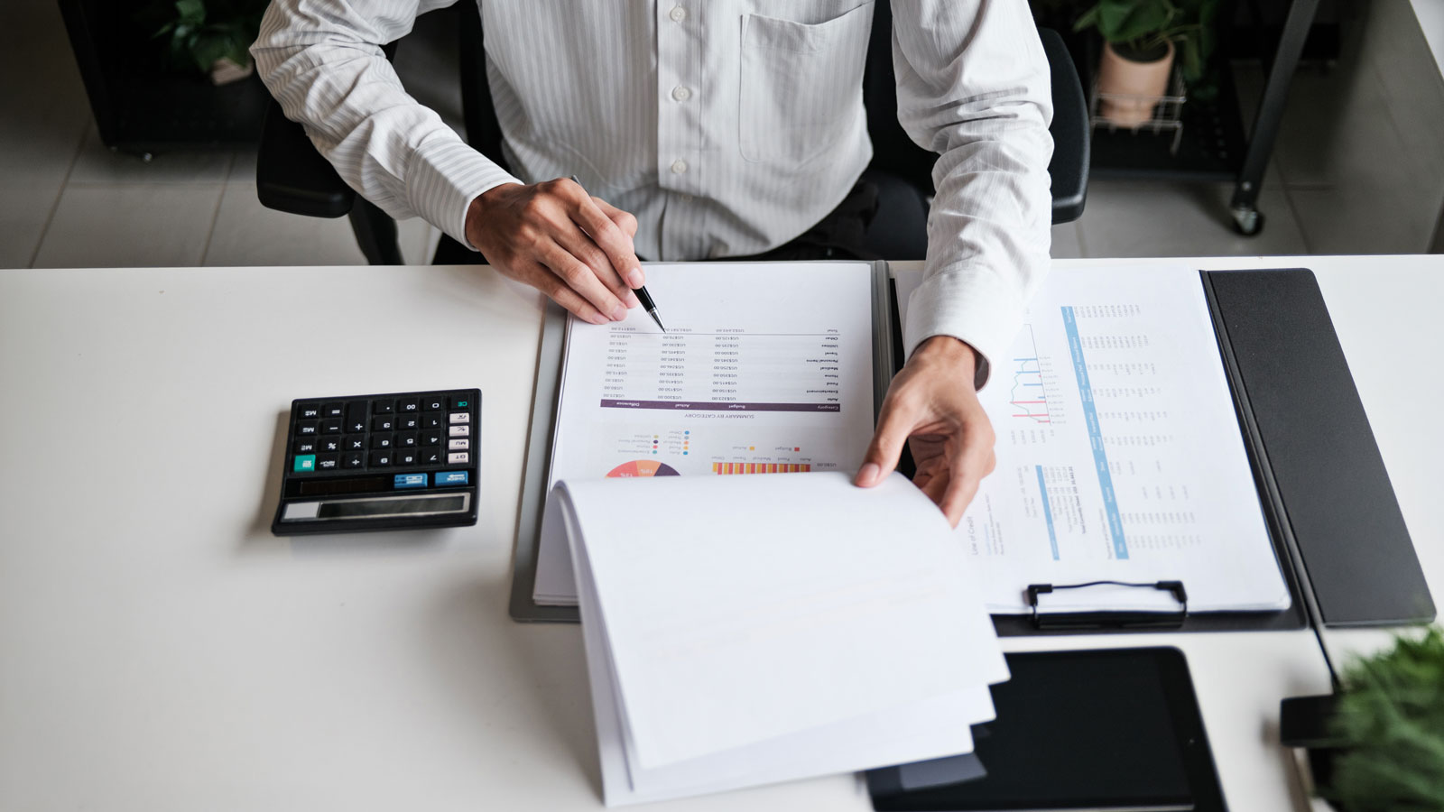 Financial admin reviewing printed data at worktable in professional office