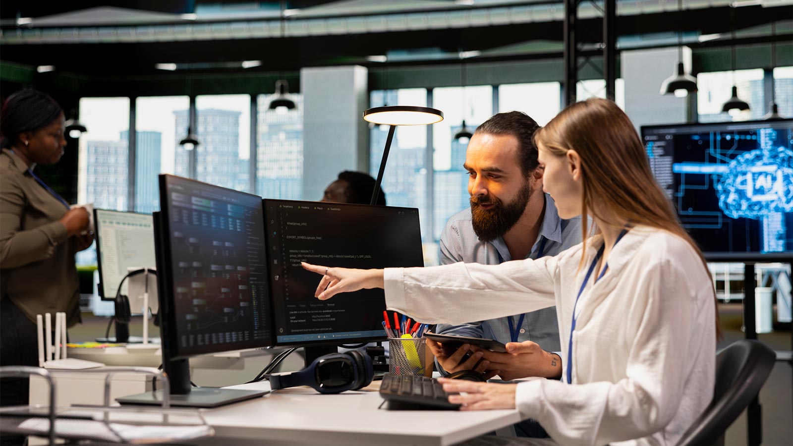 Friendly team leader mentor explaining young software engineer how to use AI tech