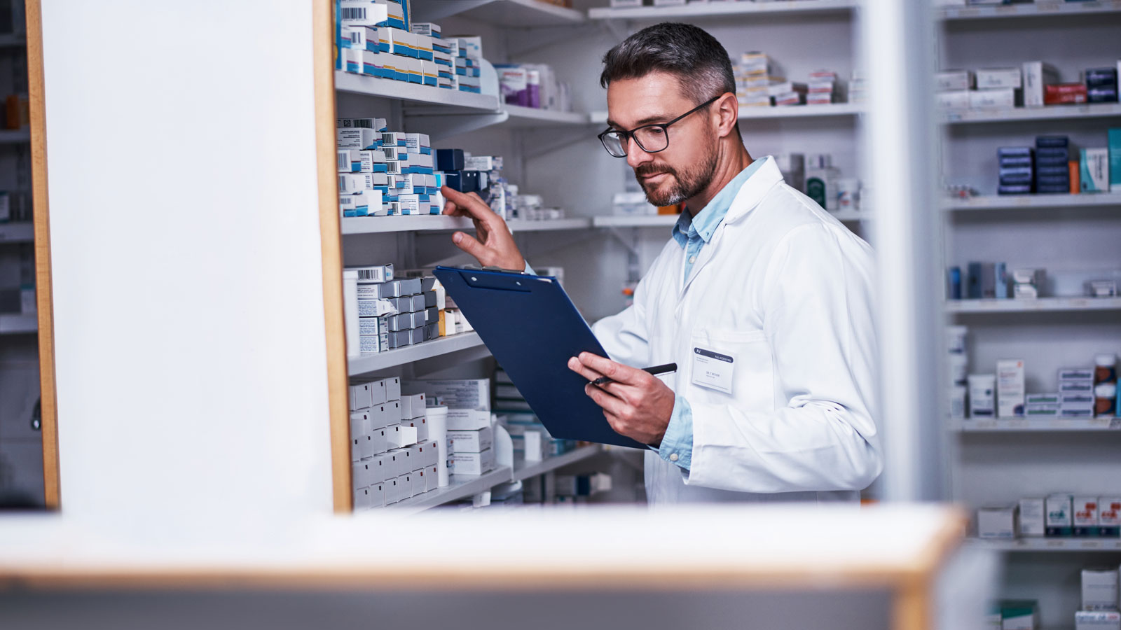 Pharmacist, man and inspection in store with checklist, medical inventory or drugs for quality control