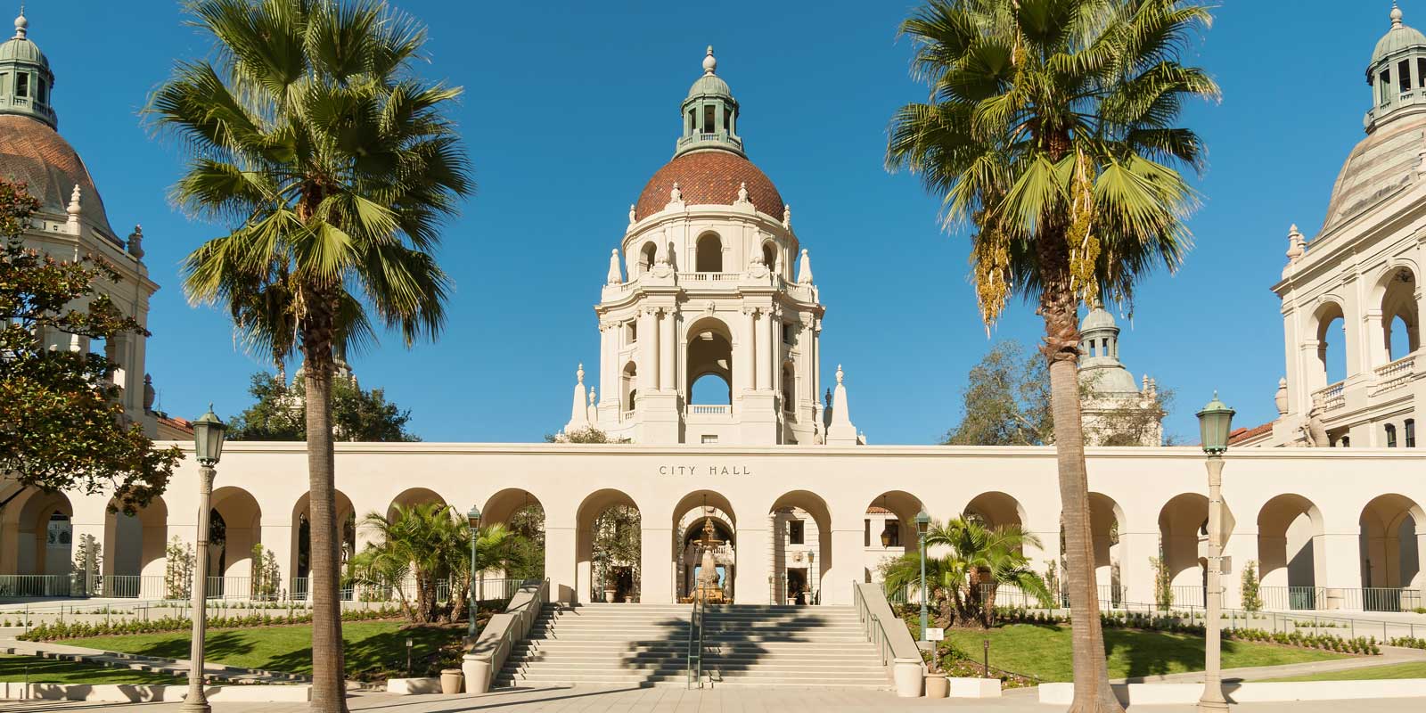 Pasadena City Hall in California, looking west, with two palm trees in the foreground under a clear blue sky.