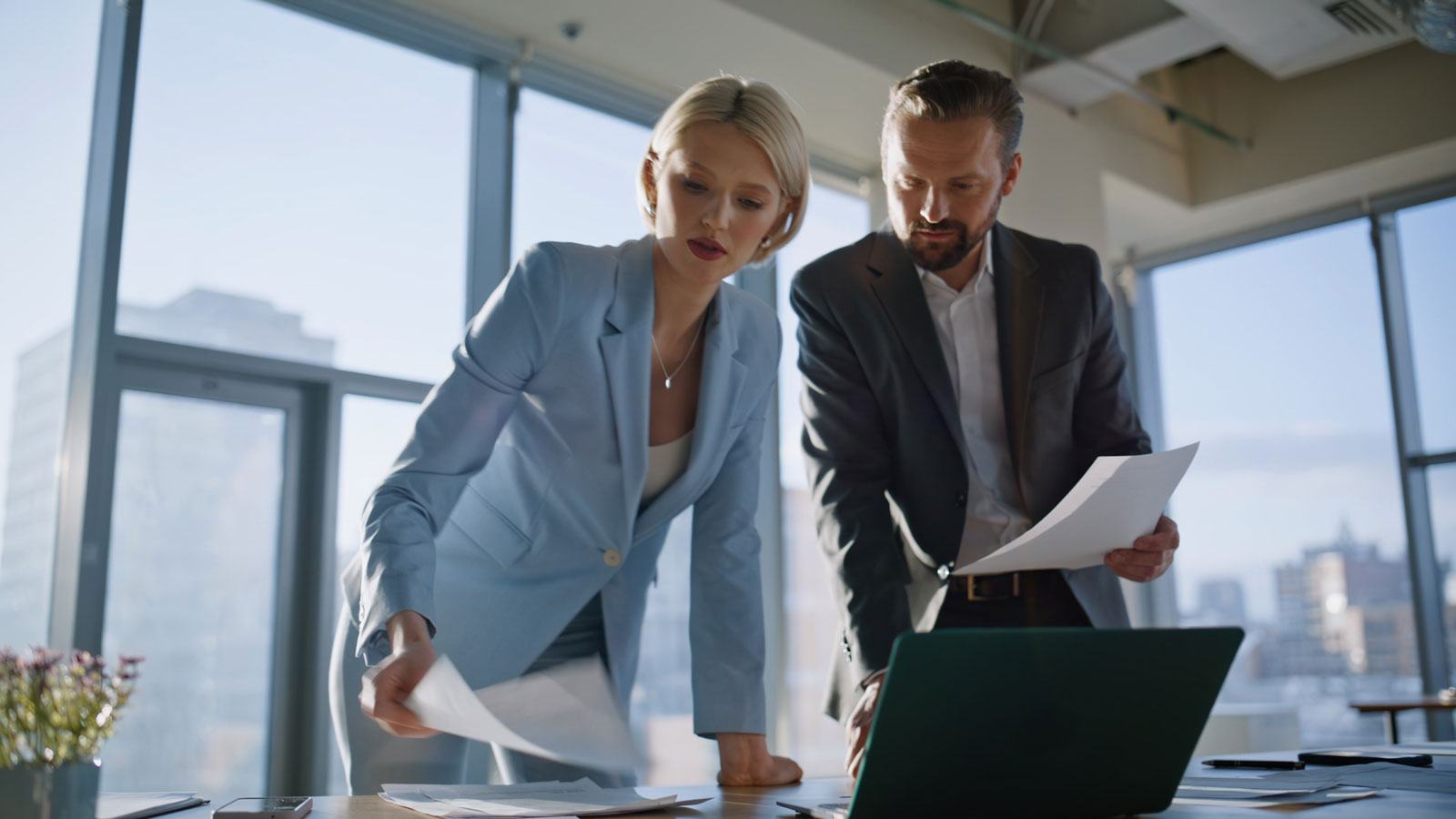 Legal professionals examining papers sunny office. Partners reviewing contract